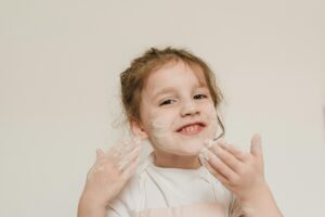 Uśmiechnięta dziewczynka z mąką na twarzy podczas zabawy plastycznej